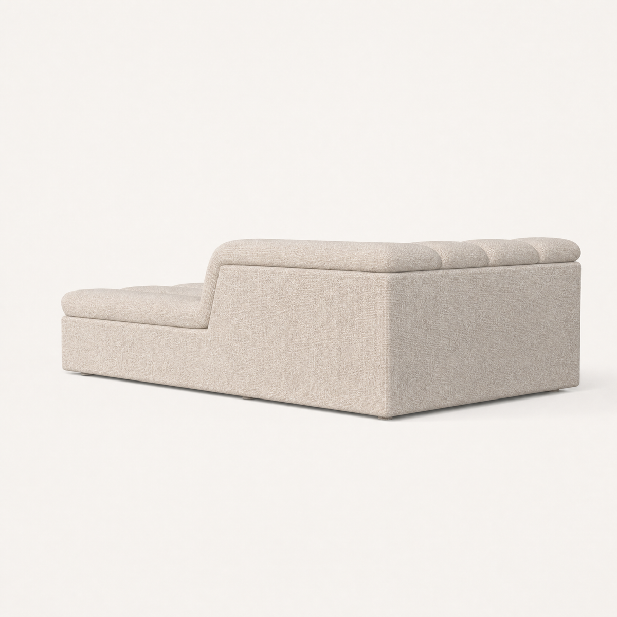 The Devi Chaise Module features textured Stone Beige performance upholstery, soft curves, and a low architectural profile.