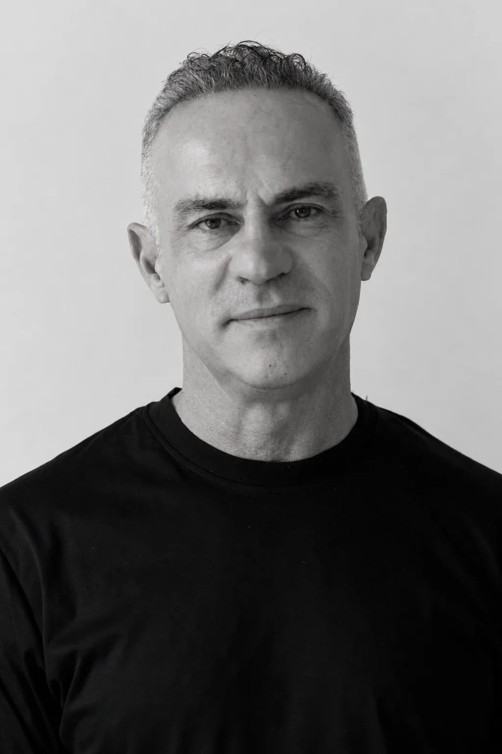 Black and white portrait of a man wearing a black t-shirt against a plain background.