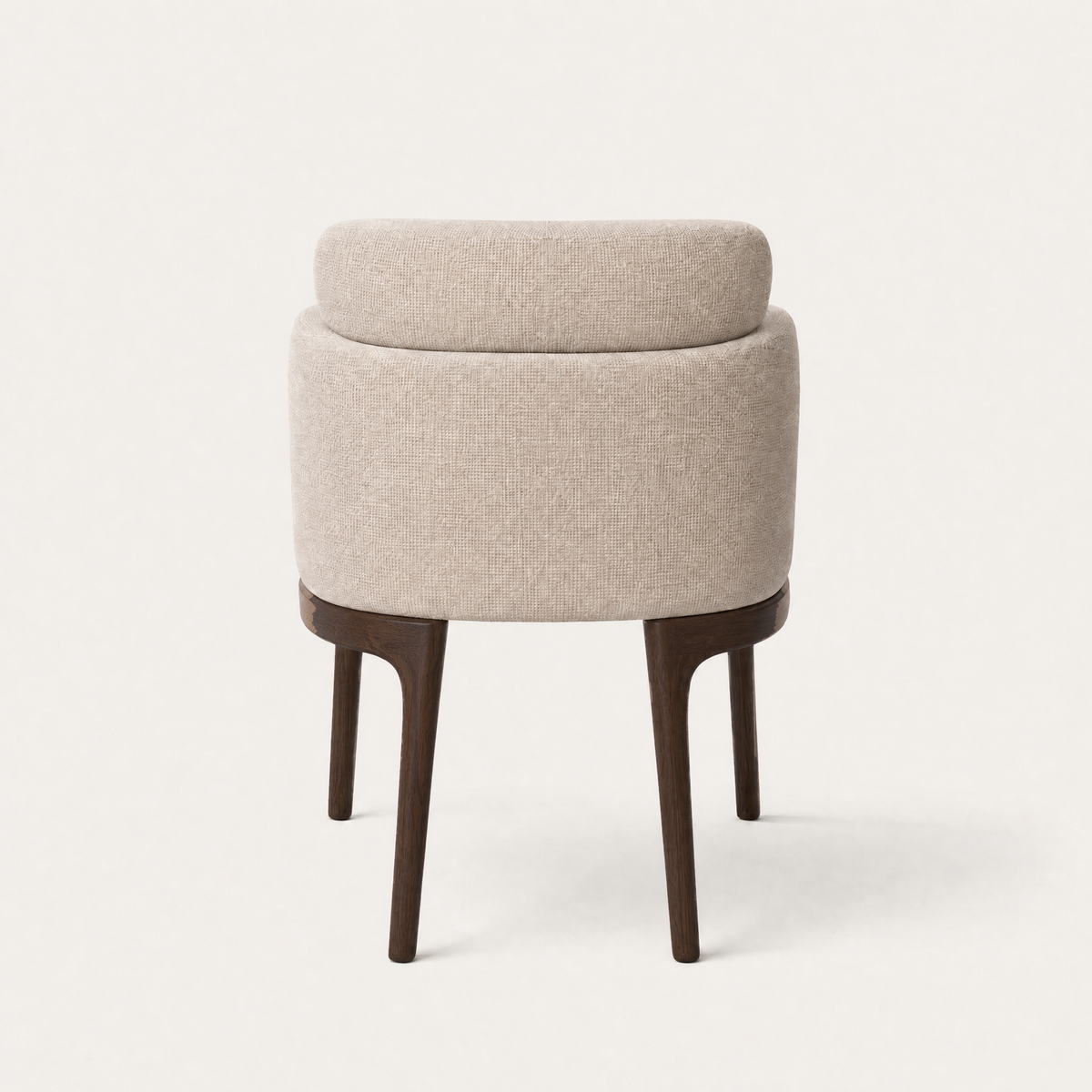 Soft upholstery wraps around the Sia Dining Chair by Ramón Esteve, while a floating lumbar cushion and tapered oak legs define its silhouette at ACERKA Miami.