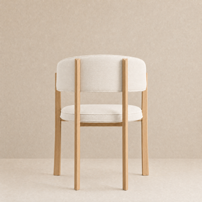 A modern dining chair with a light beige upholstered seat and curved backrest, supported by a natural light wood frame, set against a neutral beige textured background.
