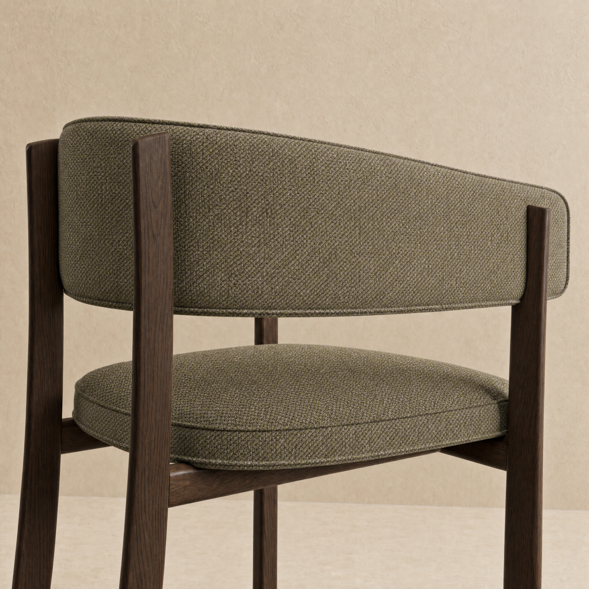 A close-up of a modern upholstered chair with a textured olive green fabric seat and backrest, supported by dark brown wooden legs, set against a neutral beige background.